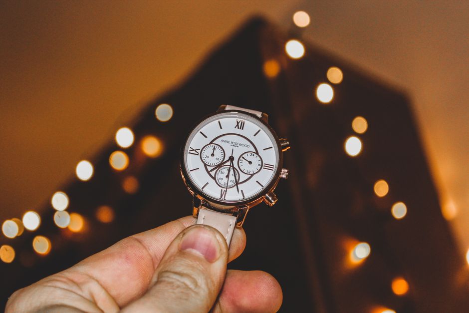 Elegant wristwatch with Roman numerals held in hand against a bokeh backdrop.